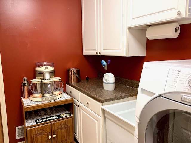 washroom featuring cabinet space, washer / clothes dryer, and a sink