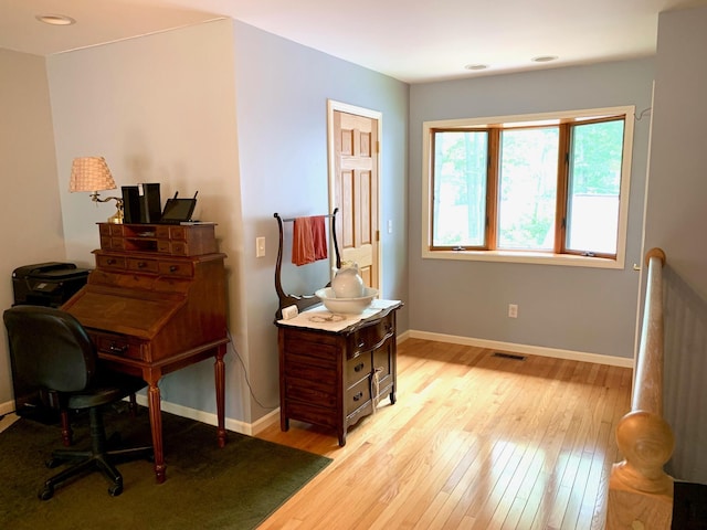 office featuring baseboards, visible vents, and light wood finished floors