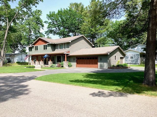 view of front of house featuring a garage, aphalt driveway, a front yard, and covered porch