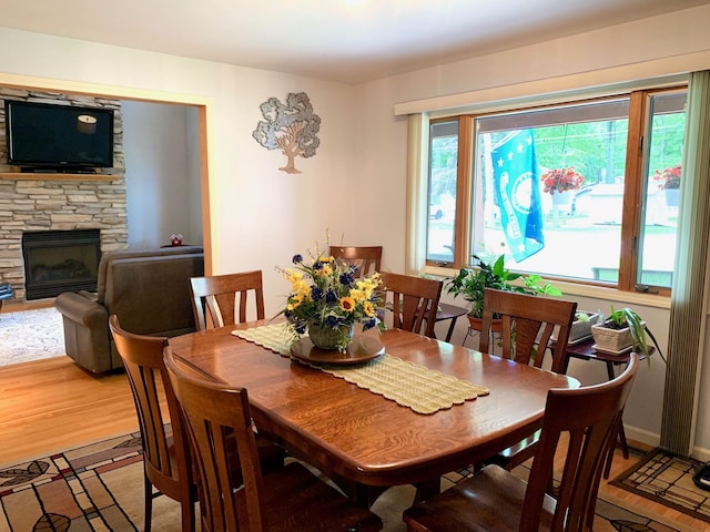 dining space with baseboards, a fireplace, wood finished floors, and a healthy amount of sunlight