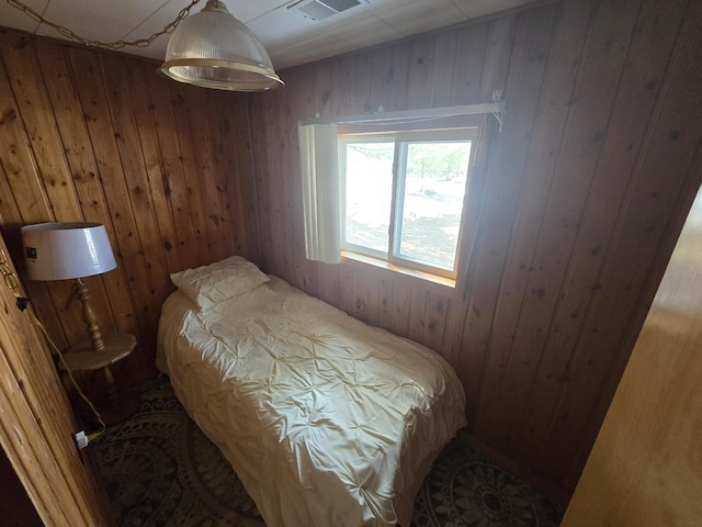 bedroom with wood walls and visible vents