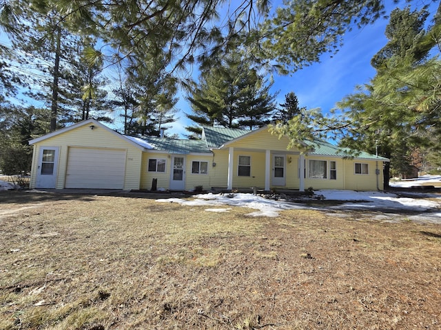 single story home featuring a garage, metal roof, and driveway