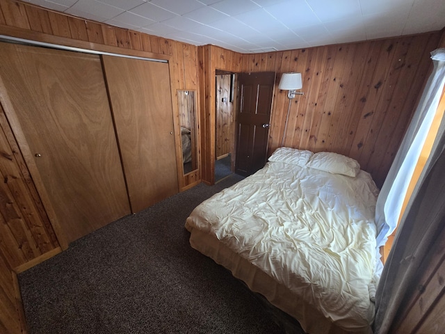 bedroom with a closet, carpet flooring, and wooden walls