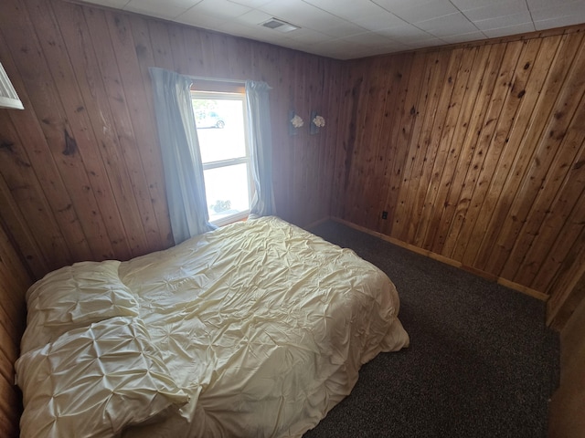 bedroom with carpet floors, baseboards, wooden walls, and visible vents