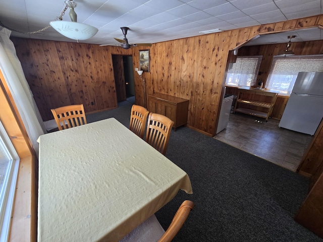 carpeted dining space with wooden walls