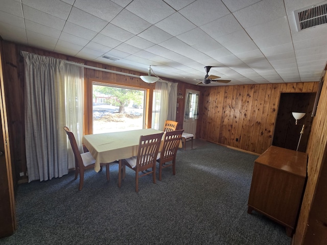 carpeted dining space featuring wood walls and visible vents