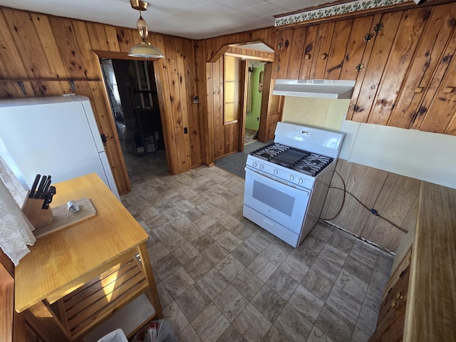 kitchen featuring white appliances, wooden walls, under cabinet range hood, and brown cabinetry