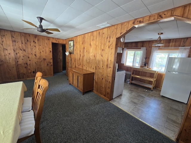 unfurnished dining area with a ceiling fan, carpet, visible vents, and wood walls