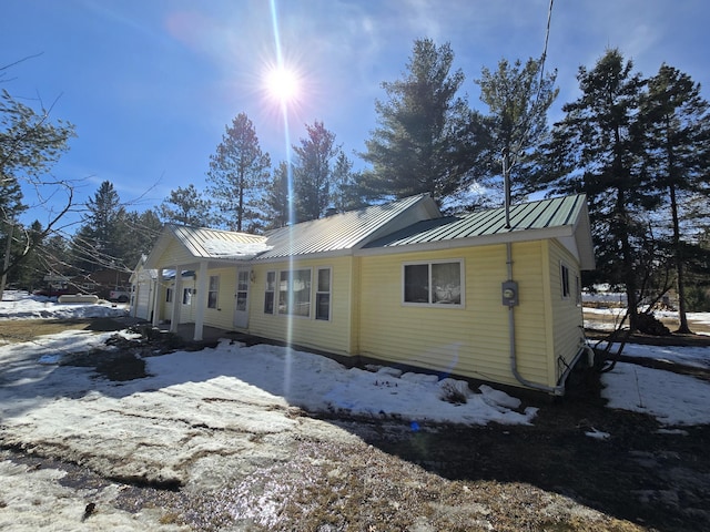 view of snow covered exterior with a standing seam roof and metal roof