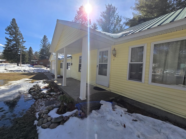 view of snowy exterior with a garage and metal roof