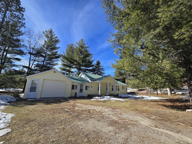 view of front of home featuring a garage, metal roof, and driveway