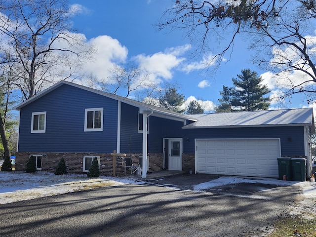 split level home with an attached garage and aphalt driveway