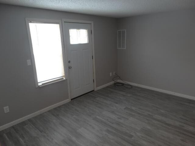 foyer featuring visible vents, a textured ceiling, baseboards, and wood finished floors