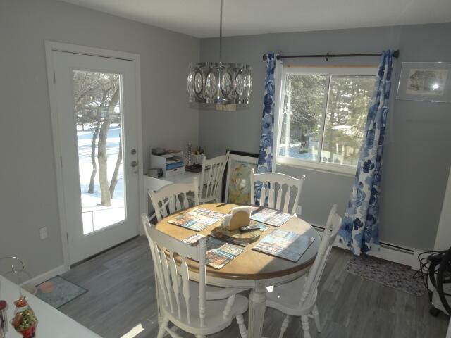 dining area with baseboard heating, wood finished floors, and an inviting chandelier