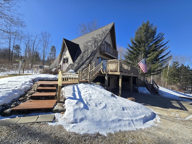 view of snow covered exterior featuring stairway, a wooden deck, and a balcony