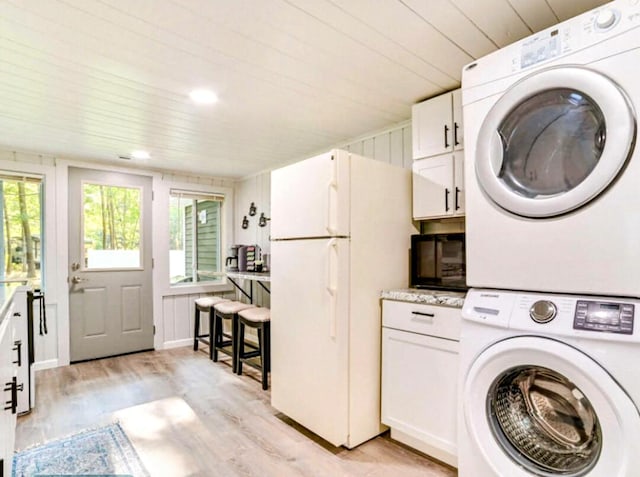 clothes washing area featuring laundry area, wooden ceiling, stacked washing maching and dryer, and light wood-type flooring