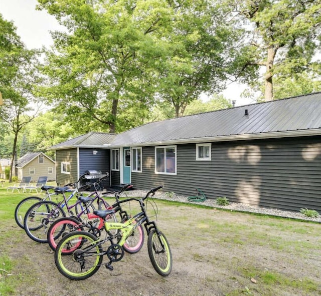 back of house with metal roof and a yard