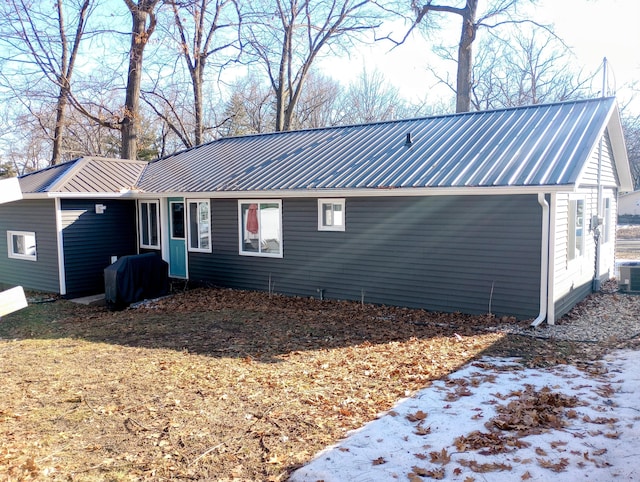 view of side of home with central AC unit and metal roof