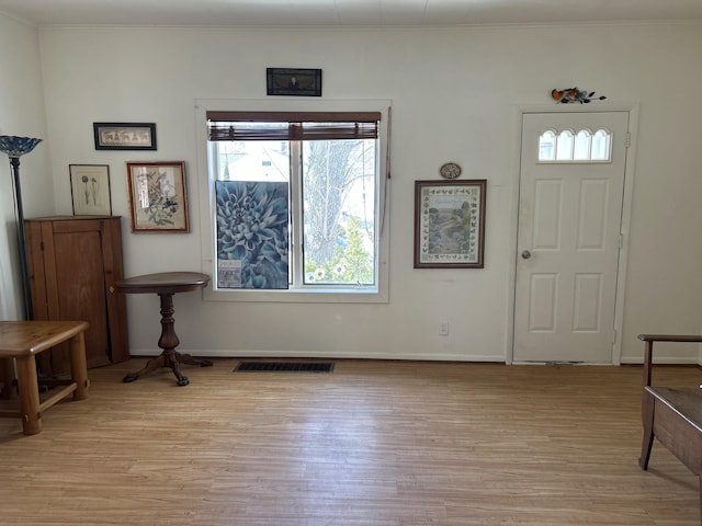 entrance foyer with light wood-style floors, visible vents, and ornamental molding