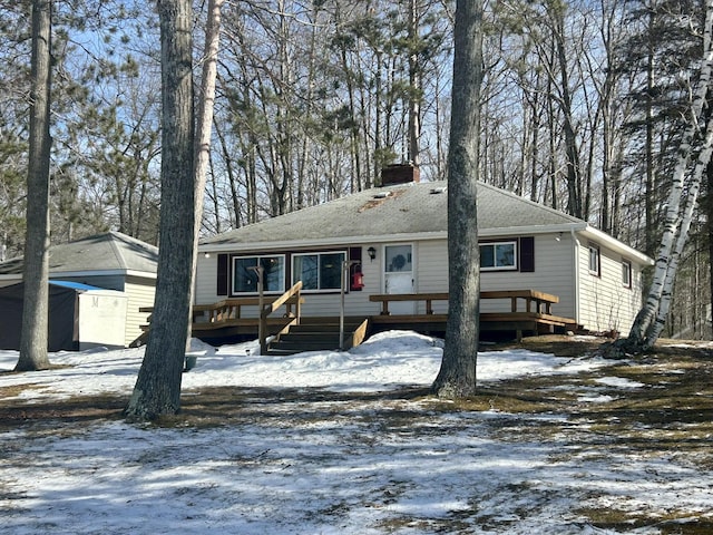 view of front facade with a deck, a chimney, and a shingled roof