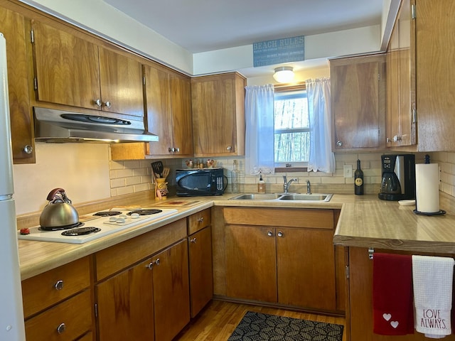 kitchen with black microwave, under cabinet range hood, light countertops, white electric stovetop, and a sink