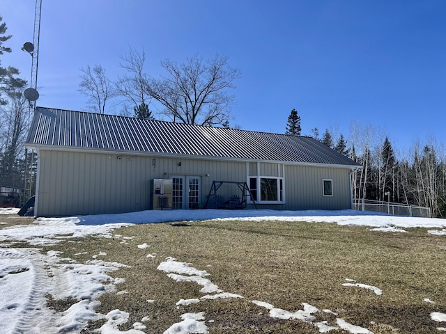 snow covered back of property featuring metal roof