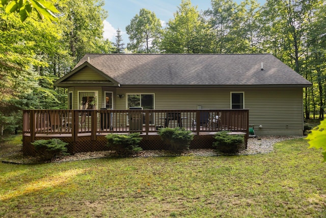 rear view of house with a wooden deck, a lawn, and a shingled roof