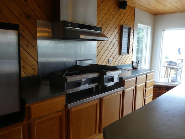 kitchen with wall chimney range hood, wood ceiling, and wooden walls