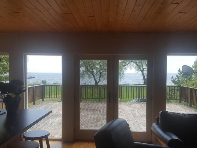 doorway with a water view, wooden ceiling, and light wood-type flooring