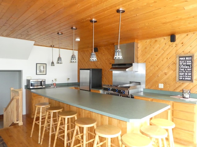 kitchen featuring a center island, refrigerator, a kitchen bar, wood ceiling, and hanging light fixtures