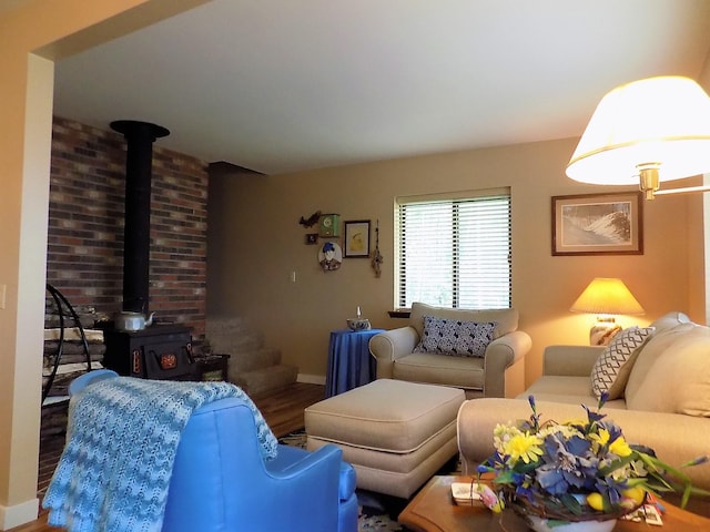 living room featuring brick wall, a wood stove, and wood-type flooring