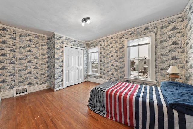 bedroom with a closet, ornamental molding, hardwood / wood-style floors, and multiple windows