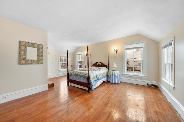 bedroom featuring multiple windows, vaulted ceiling, and light wood-type flooring