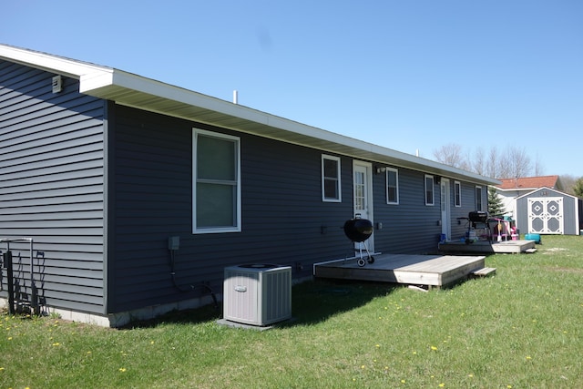 back of house featuring a wooden deck, a storage shed, central air condition unit, and a lawn