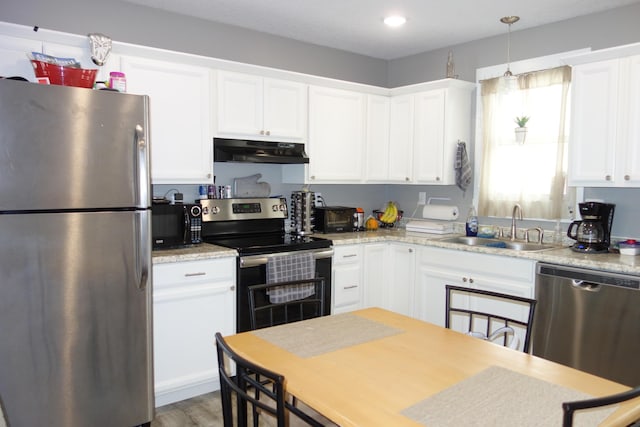 kitchen featuring sink, exhaust hood, hanging light fixtures, white cabinets, and stainless steel appliances