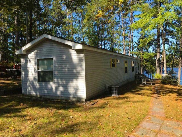 view of side of property featuring central air condition unit and a lawn