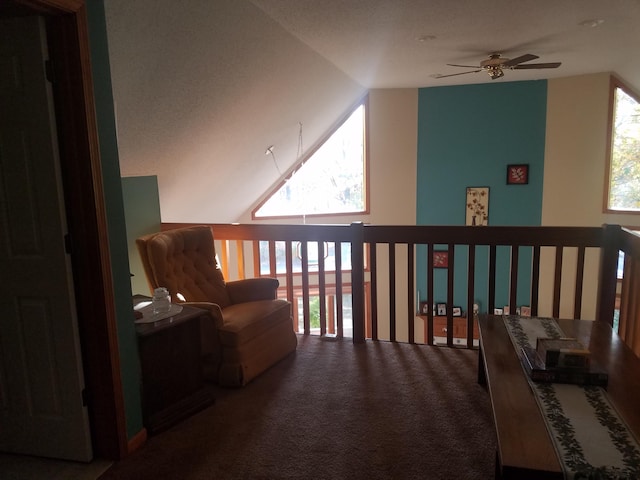 living area featuring dark colored carpet, a healthy amount of sunlight, vaulted ceiling, and ceiling fan