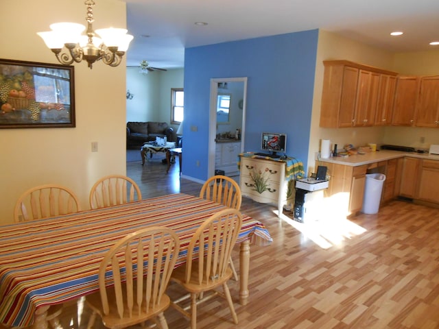 dining space with light hardwood / wood-style floors and ceiling fan with notable chandelier