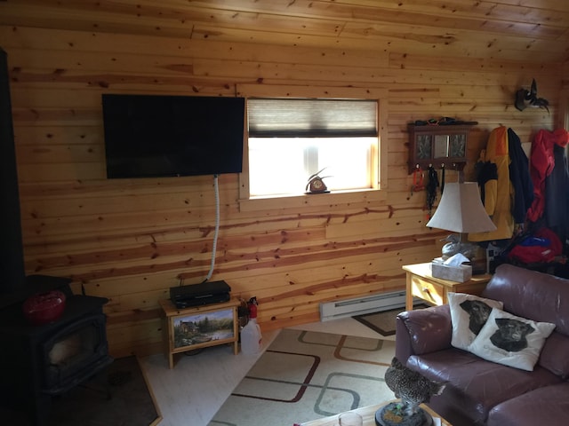 living room featuring wood walls, a baseboard radiator, a wood stove, and carpet