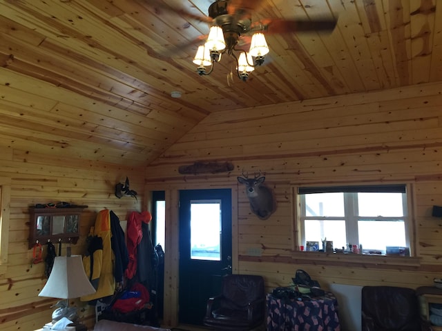 interior space with wood ceiling, wooden walls, and ceiling fan