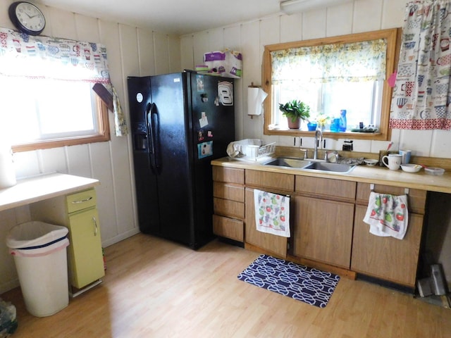 kitchen with light hardwood / wood-style floors, black fridge with ice dispenser, and sink