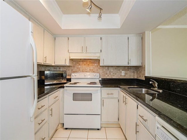 kitchen featuring a raised ceiling, dark stone countertops, sink, and white appliances