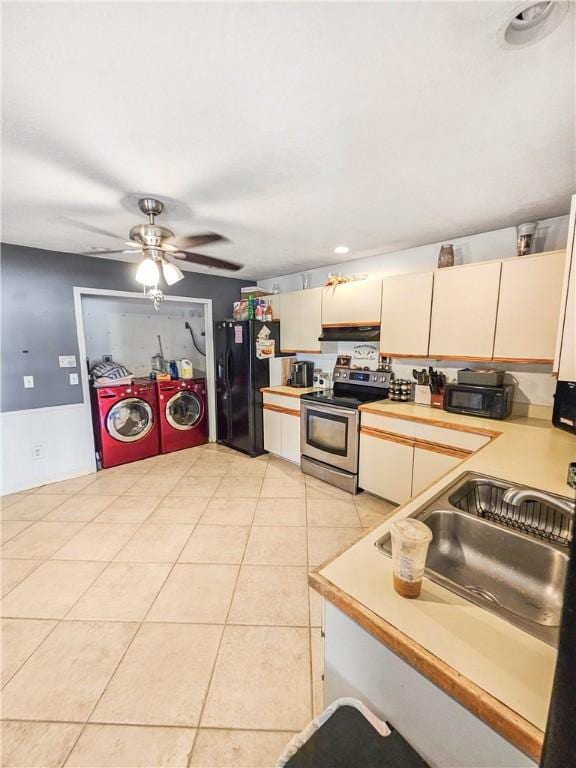 kitchen with light tile patterned floors, ceiling fan, washing machine and dryer, cream cabinets, and black appliances