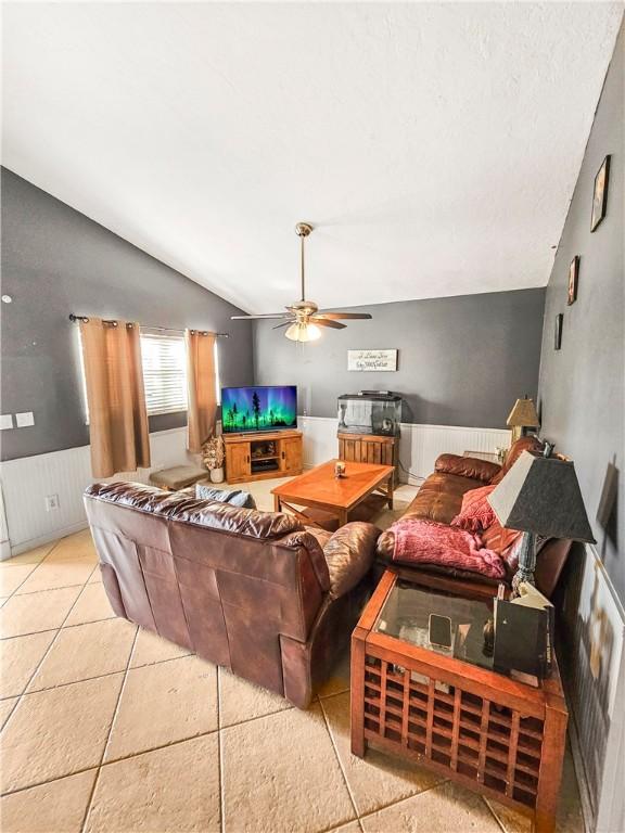 living room featuring ceiling fan, lofted ceiling, and light tile patterned floors