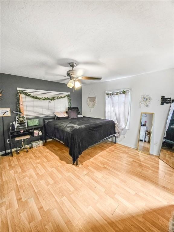 bedroom featuring ceiling fan, wood-type flooring, and a textured ceiling