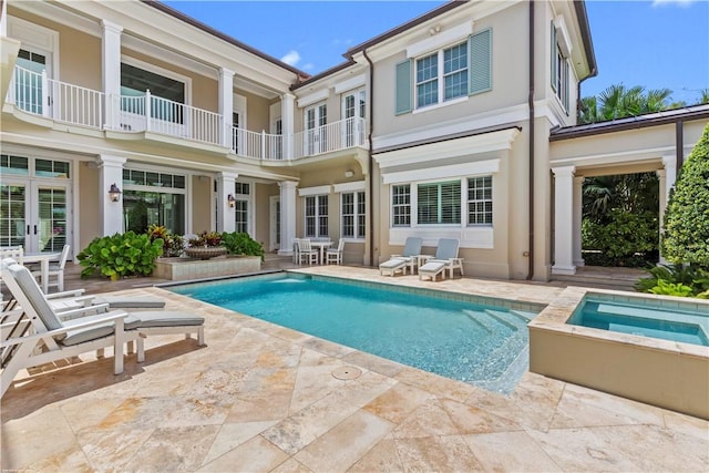 back of property with a patio area, an in ground hot tub, and stucco siding