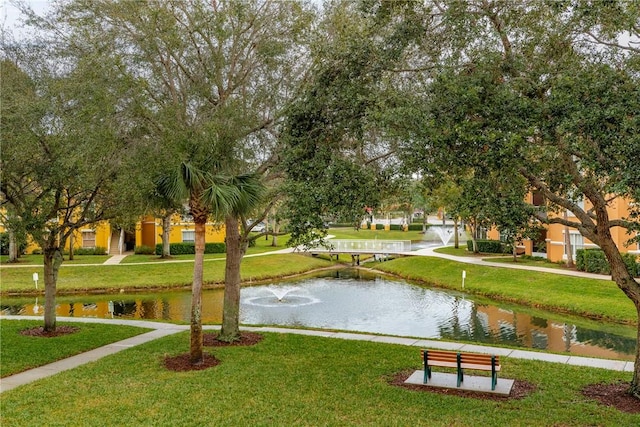 view of property's community with a lawn and a water view