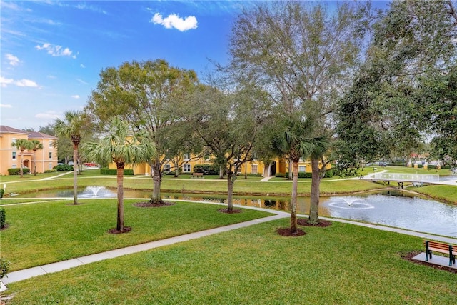 view of home's community with a water view and a lawn