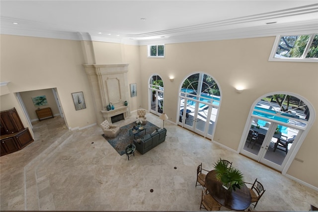 living room with french doors, a towering ceiling, ornamental molding, and a fireplace