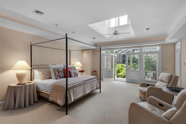 bedroom with a raised ceiling, carpet floors, access to exterior, and a skylight